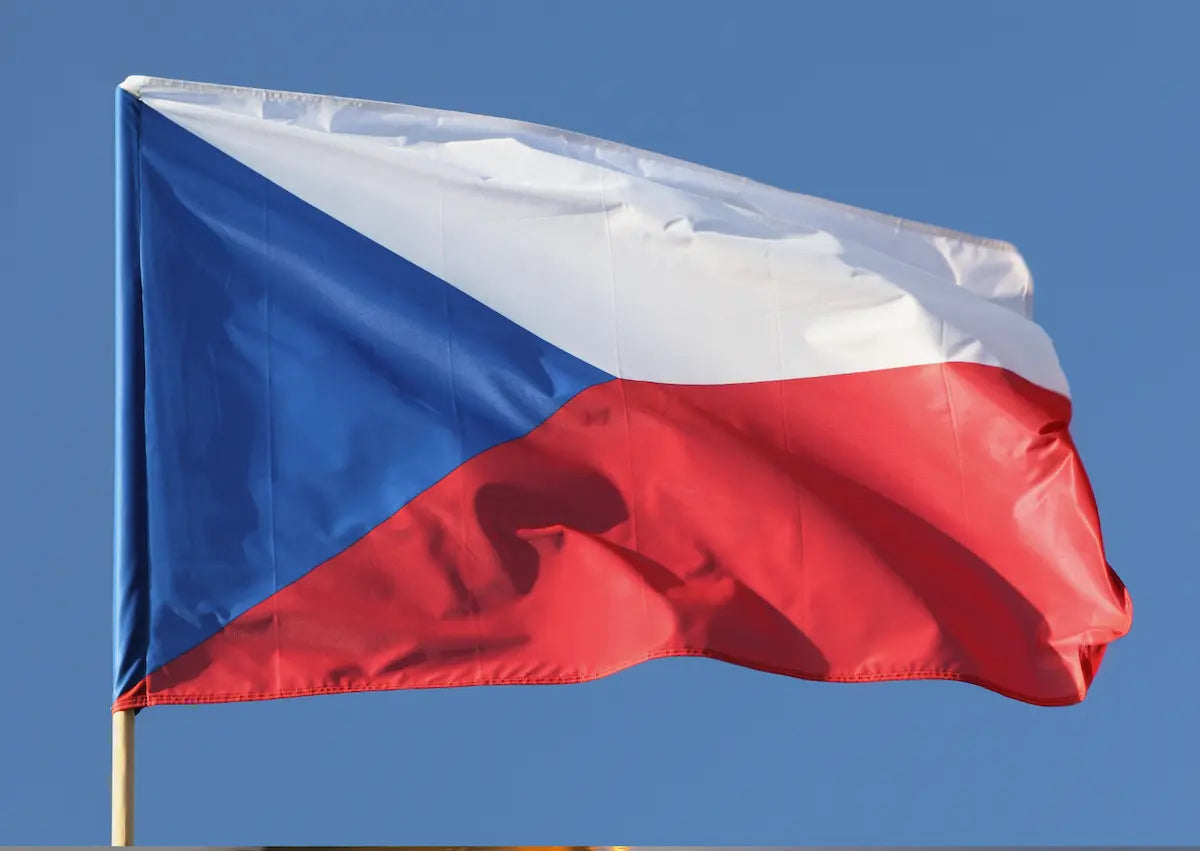 Die tschechische Nationalflagge mit dem markanten blauen Dreieck sowie weißen und roten Balken weht vor blauem Himmel – Zur digitalen Vignette Tschechien (E-Vignette) auf mautbox24.com.