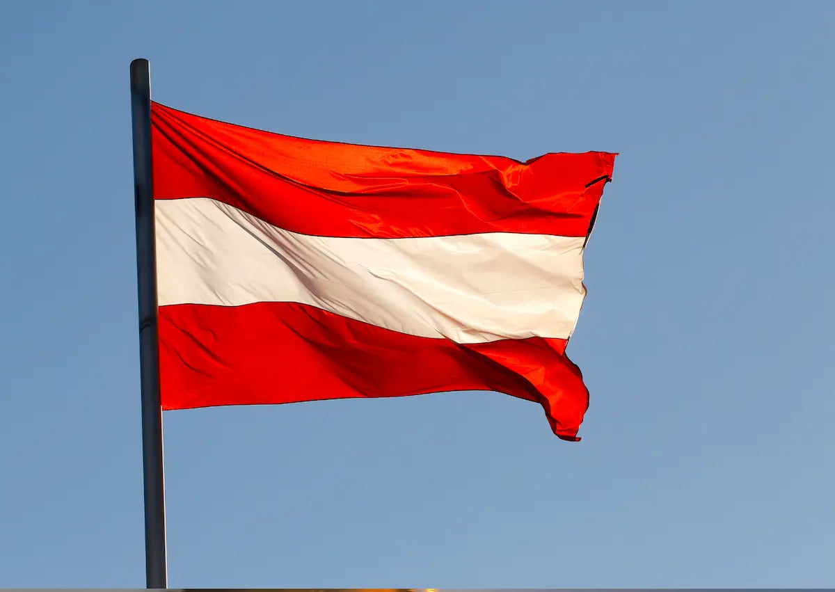 Die Fahne von Österreich weht im Wind  Im Hintergrund der blaue Himmel – Zur digitalen Vignette Österreich (E-Vignette) auf mautbox24.com.